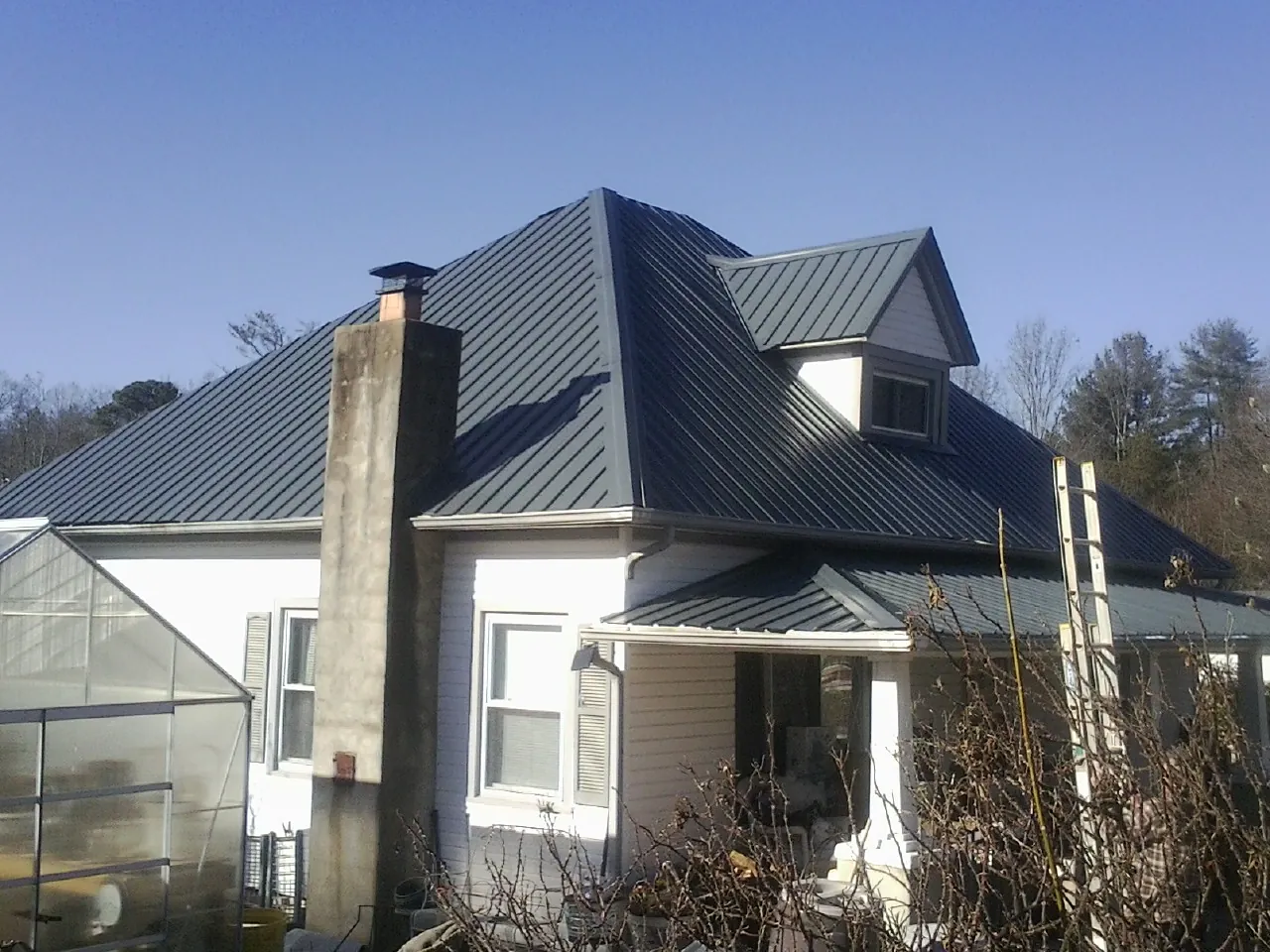 Dark blue standing seam metal roof on a white farmhouse with dormer — Slate & Tile Roof Repair by Roofing Brothers in Dillwyn