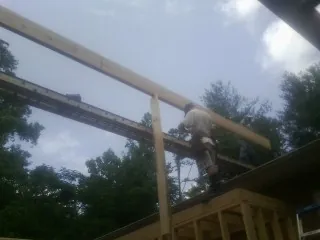Carpenter setting a ridge beam over a new addition frame — Ice Dam Removal by Roofing Brothers in Dillwyn