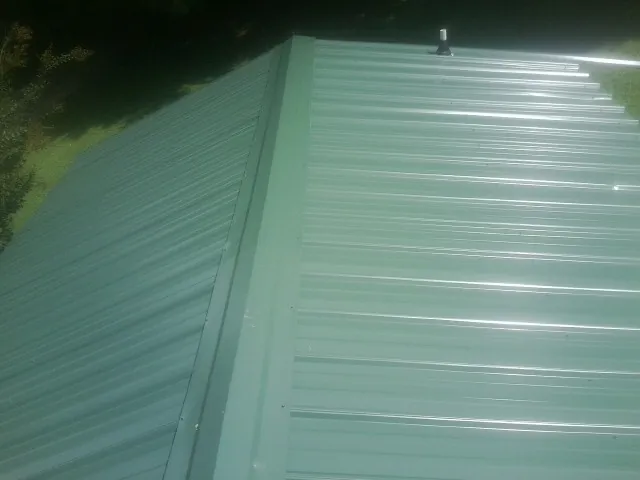 New green metal panels meeting at the ridge of a roof — Flat Roof Repair work by our crew in Dillwyn