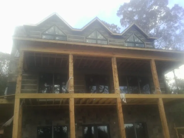 Dormers and porch framing on a large log home under construction — Roof Coating work by our crew in Dillwyn