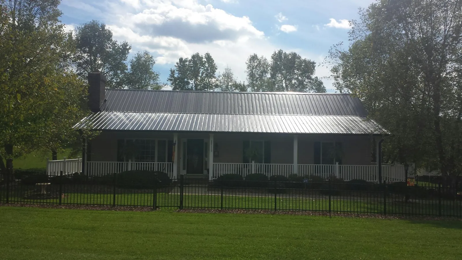 Gray metal roof on a brick ranch with a full width front porch — Gutter Guard Installation work by our crew in Dillwyn