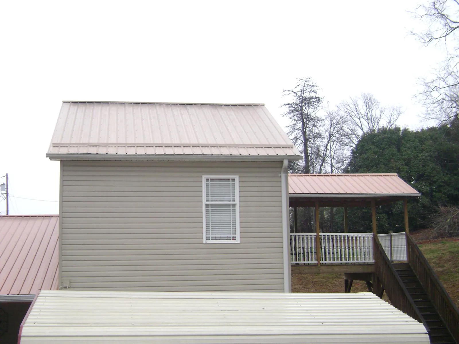 Tan metal roofs on a two story addition and attached porch, from a Roof Replacement job in Dillwyn