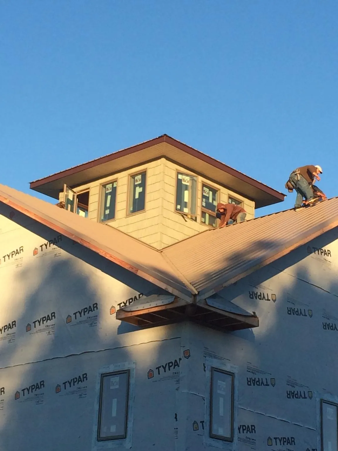 Roofers working around a rooftop cupola on a new metal roof at sunset — Roof Waterproofing in Dillwyn by Roofing Brothers